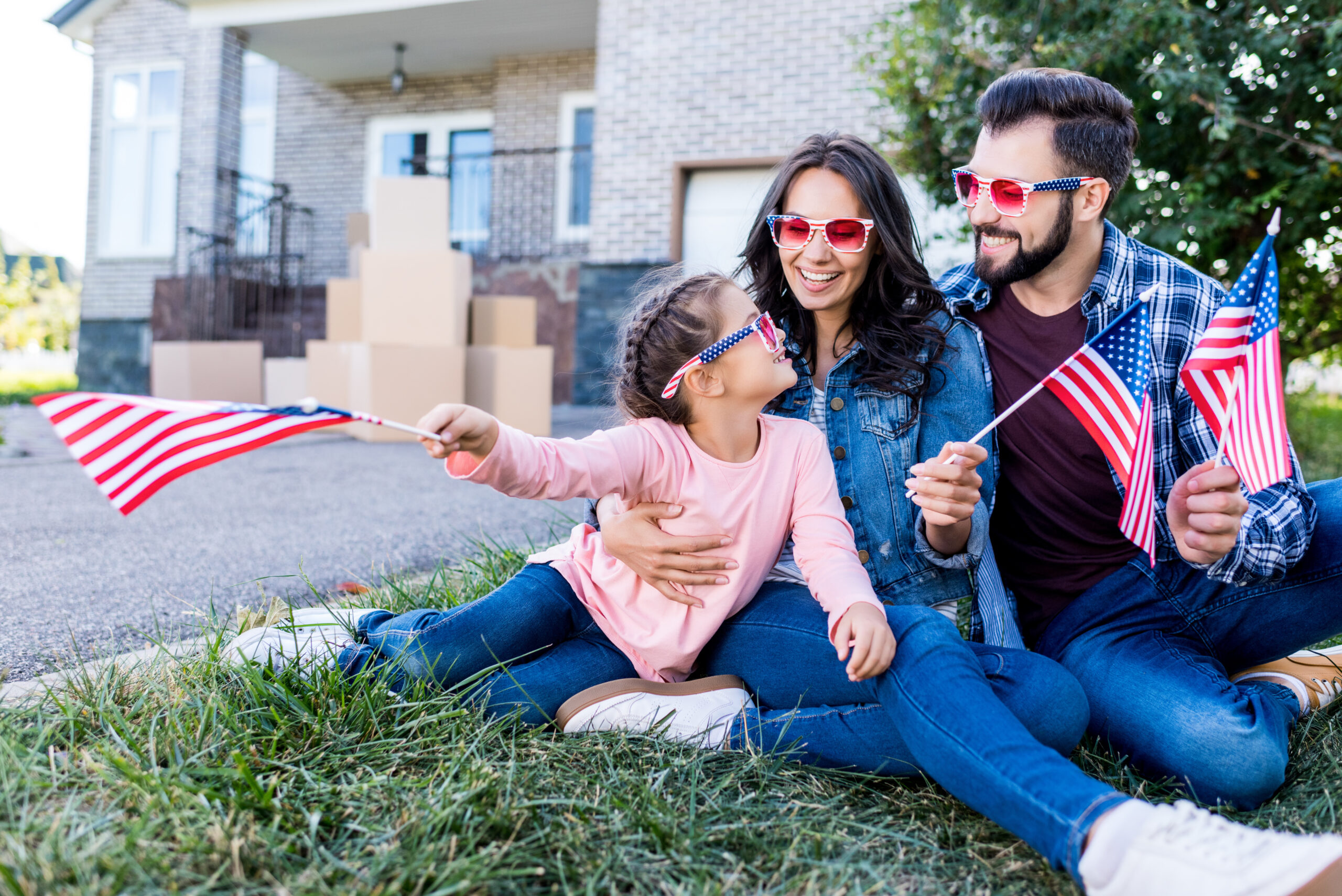 Family,With,American,Flags,And,Sunglasses,Sitting,In,Garden,Of